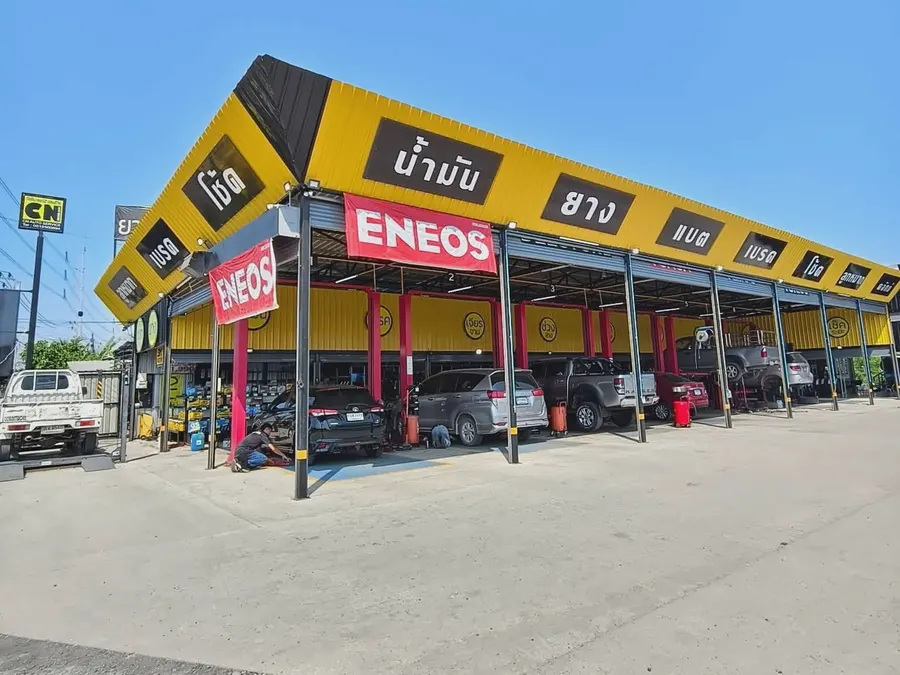 หน้าร้าน CN Auto Service ตอนกลางวัน เห็นป้ายบริการน้ำมัน ยาง แบต เบรค โช้ค และรถที่กำลังเข้ารับบริการในช่องยก